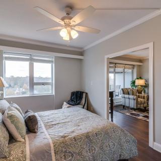 A cozy bedroom with a ceiling fan, large windows, and soft-colored decor.