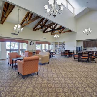 A spacious room with high ceilings and wooden beams, featuring a dining and seating area with elegant chandeliers.