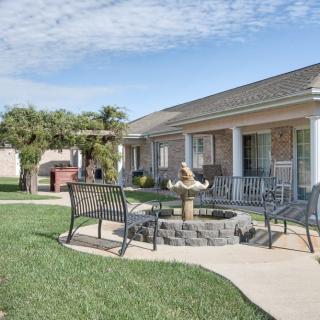 A cozy outdoor seating area with a fountain and chairs on a patio in front of a house.