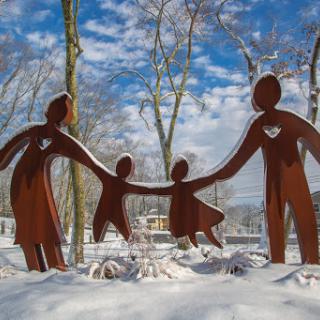 A family-themed sculpture stands gracefully in the snowy landscape, symbolizing unity and togetherness.