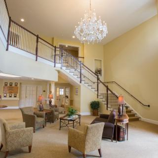 Spacious living area with elegant chandelier and grand staircase.