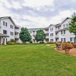 A view of a residential apartment building with a landscaped courtyard and benches.