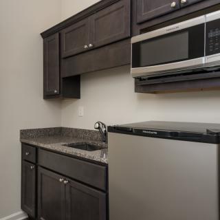 A modern kitchen setup featuring dark cabinets, a compact fridge, and a microwave.