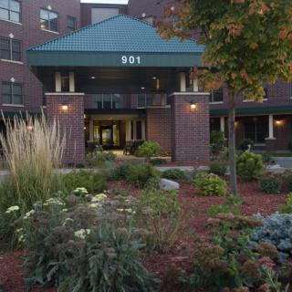 A well-landscaped entrance to a brick building surrounded by greenery.