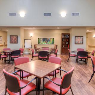 A spacious dining area with multiple tables and chairs, featuring warm lighting and a wood floor.