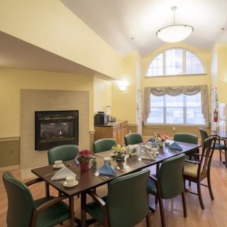 A cozy dining room with a large table, chairs, and a fireplace.