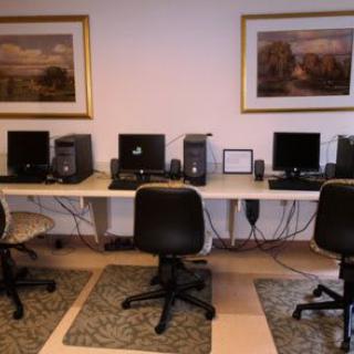 A computer lab with multiple workstations and chairs arranged neatly.