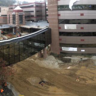 A view of a construction site featuring modern buildings and a connecting bridge.