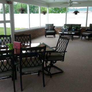 A cozy outdoor patio area with seating and tables surrounded by large windows.