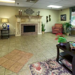 A cozy lobby interior featuring a fireplace, comfortable seating, and decorative plants.