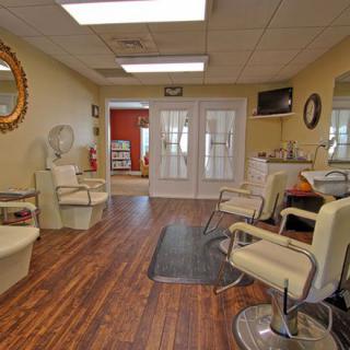A cozy and well-lit salon interior with multiple chairs, mirrors, and wooden flooring.