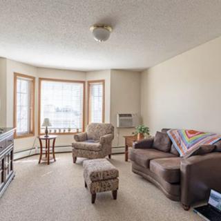 A cozy living room featuring a sofa, armchair, and large window.