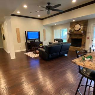 A cozy living room with a television, sofas, and a fireplace featuring a large clock on the mantel.