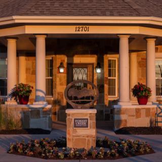 A charming house with a welcoming front porch, featuring pillars and neatly arranged landscaping.