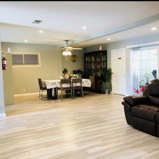 A modern living and dining area with hardwood floors, featuring a ceiling fan and indoor plants.
