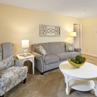 A cozy living room featuring a sofa, armchairs, coffee table, and decorative elements.