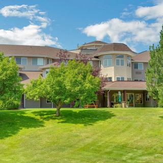 A residential building with a spacious lawn and trees on a sunny day.