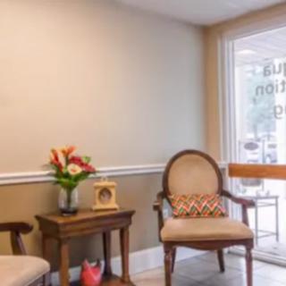 A cozy waiting room with comfortable chairs, a small table adorned with flowers, and a welcoming atmosphere.