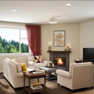 A cozy living room with a fireplace, comfortable sofas, and a view of the outdoors through the window.