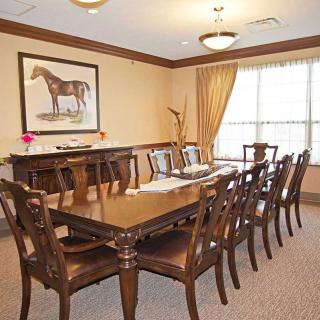 Elegant dining room with a long table, chairs, and horse artwork on the wall.