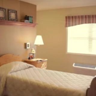 A neatly arranged hospital bedroom with a single bed and soft lighting.