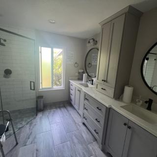 A modern bathroom with sleek cabinetry, dual mirrors, and a spacious walk-in shower.