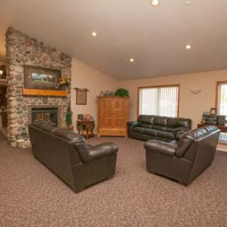 A cozy living room featuring a stone fireplace, leather sofas, and carpeted flooring.