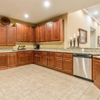 A spacious kitchen with wooden cabinets and granite countertops, featuring modern appliances and recessed lighting.