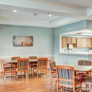 A cozy dining area with wooden tables and chairs, adjacent to an open kitchen.