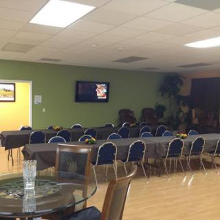 A quiet meeting room with neatly arranged tables and chairs, featuring a television on the wall.