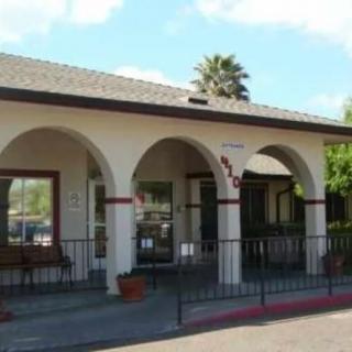 Front view of a building with arches and a palm tree in the background.