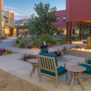 A cozy outdoor patio area with seating and a fire pit surrounded by landscaped gardens.