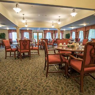 An elegant dining room with neatly arranged tables and chairs, decorated with warm lighting and curtains.