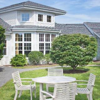 A beautiful suburban house with a well-maintained garden and patio furniture in the yard.