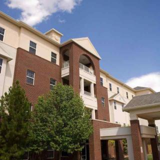 Exterior view of a multi-story residential building with a mix of brick and light-colored siding.
