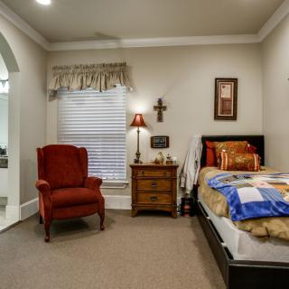 A cozy bedroom with a single bed, armchair, nightstand, and decorative items.