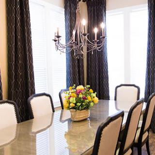 A sophisticated dining room with an elegant chandelier, floral centerpiece, and plush chairs surrounding a polished table.