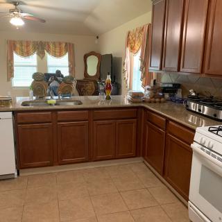 A spacious kitchen with wooden cabinets, a countertop, and various appliances including a stove and dishwasher.