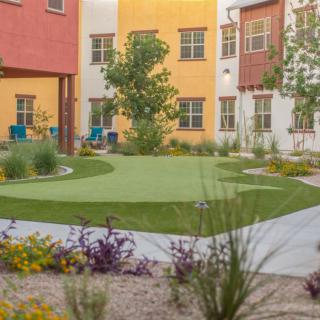 A colorful apartment complex courtyard with landscaped greenery and pathways.
