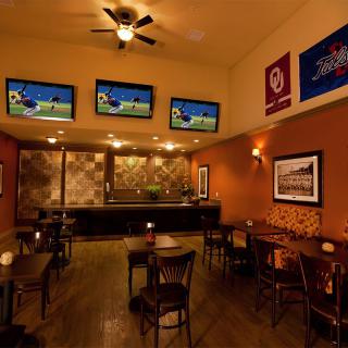 A cozy bar with multiple TV screens showing sports and empty seating areas.
