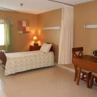 A hospital room featuring a single bed, desk, and privacy curtain.