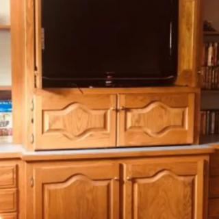 A wooden cabinet with a television and bookshelf.