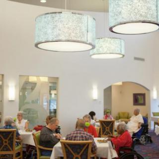 A cozy dining room with several people seated at tables under elegant chandeliers.