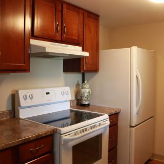 A kitchen with wooden cabinets, a white stove, and a refrigerator.