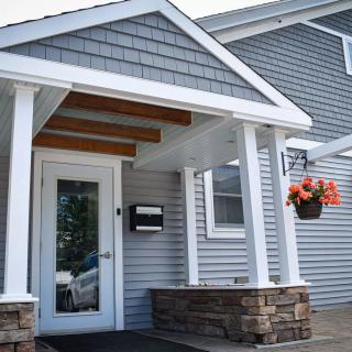 A modern house entrance with a small porch and hanging flower basket.