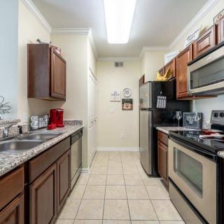 A modern kitchen with stainless steel appliances and wooden cabinets along a narrow layout.