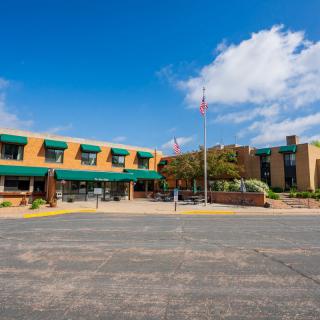A hotel with green canopies and a parking lot under a partly cloudy sky.