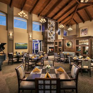 A cozy restaurant dining area with elegant interior design, featuring a high wooden ceiling and decorative chandeliers.