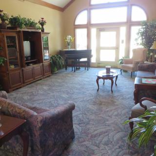A cozy living room featuring a large window, elegant furniture, and a piano.