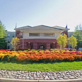 A scenic view of a building surrounded by vibrant gardens and lush trees on a sunny day.